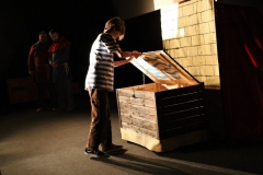 Uczennica naszej szkoły w roli aktorki (sprawdza zawartość tajemniczej skrzyni) w trakcie spektaklu „Arka wszystkich świętych”.