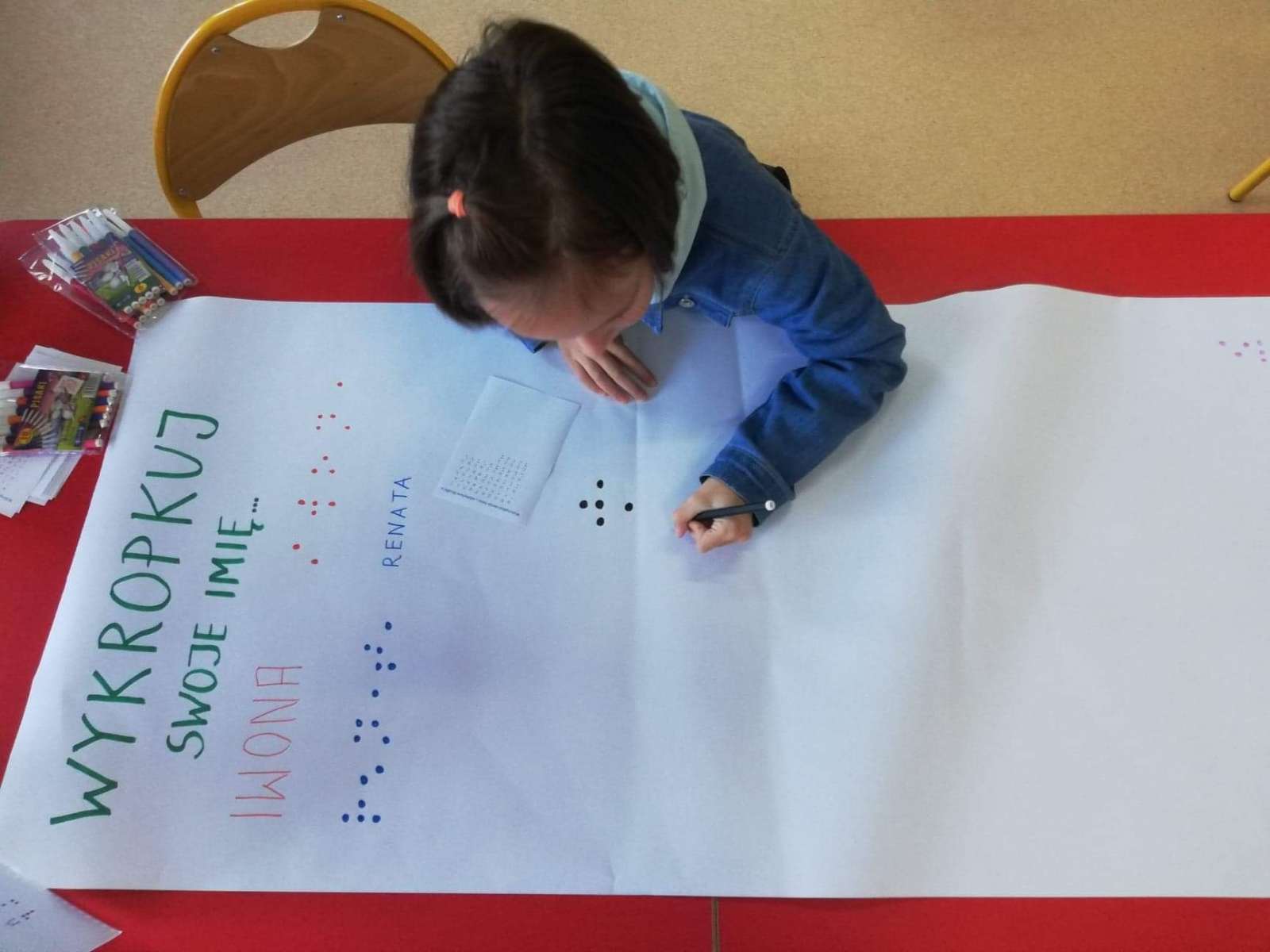 Dzieci zapisują swoje imię alfabetem Braillea.