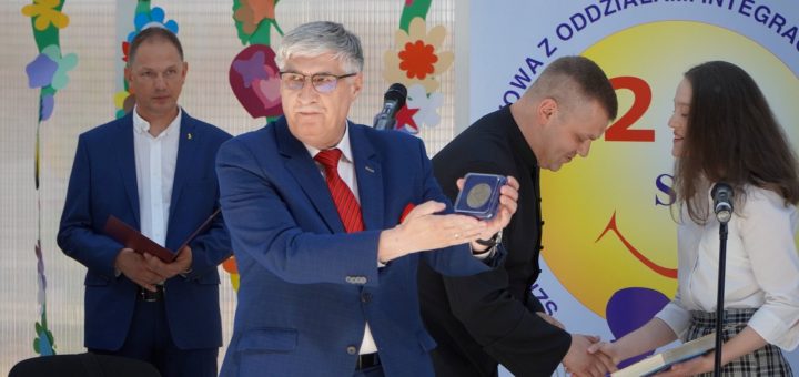 Zdjęcie przedstawia dyrektora szkoły prezentującego medal Janusza Korczaka