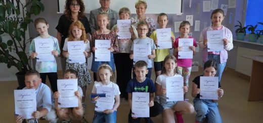 Grupa dzieci - laureaci konkursu ortograficznego prezentują dyplomy, nagrody oraz dyrektor szkoły i organizatorzy konkursu.