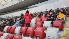 Uczniowie siedzą na trybunach Stadionu Narodowego, a nad nimi grafika piłki nożnej.