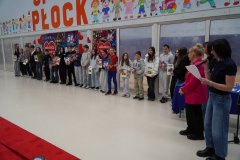 Grupa młodzieży z klas 4 – 8 odbiera nagrody za udział w szkolnej aukcji prac plastycznych. Dzieci ustawione są w rzędzie na tle dekoracji WOŚP. 