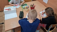 Troje dzieci koloruje flagę Polski.