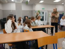 W przestronnej sali- siedzibie Klubu Seniora, przy drewnianych ławkach siedzi grupka przedstawicieli Samorządu Uczniowskiego- wszyscy słuchają stojącego obok mężczyzny- reżysera. 