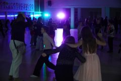 Uczniowie Szkoły Podstawowej nr 22 w Płocku tańczą i świetnie bawią się podczas pełnej energii dyskoteki andrzejkowej na kolorowo oświetlonej, przestronnej sali. 