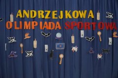 Dekoracja wykonana na potrzeby turnieju- na granatowym materiale przyczepiony napis Andrzejkowa Olimpiada Sportowa oraz elementy związane z andrzejkami: czarne nietoperze, kapelusze czarownicy, czarne koty, szklane kule, klucze wykorzystywane podczas przelewania wosku.