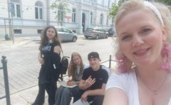 Uczniowie wraz z nauczycielem odpoczywają w trakcie gry – siedzą na barierkach na chodniku.