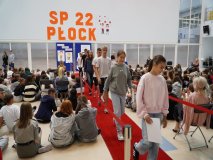 Nagrodzeni i uśmiechnięci stypendyści z klas 7-8 wracają po czerwonym dywanie na swoje miejsca.