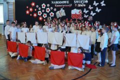 Dzieci biorące udział w apelu, trzymające białe i czerwone chusty tworzące flagę Polski.