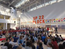 Grupa nagrodzonych stypendystów SP 22 w Płocku stoi na czerwonym dywanie podczas uroczystości, odbierając wyróżnienia