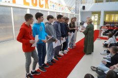 Grupa stypendystów SP 22 w Płocku stoi na czerwonym dywanie podczas uroczystości, odbierając wyróżnienia z rąk Pań Dyrektorek.