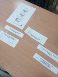Foto_8 Ułożone na ławce szkolnej, wycięte z papieru, kolejne części WPS (WYDARZENIE, PRZEKONANIE, SKUTEK) w taki sposób by pokazać negatywne przekonanie w sytuacji przeprowadzki do nowego domu i zmiany szkoły oraz wynikający z tego negatywny skutek oraz pozytywne przekonanie i również pozytywny skutek.