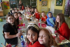 Poczęstunek w klasie 3F. Uczniowie siedzący przy stole zastawionym przekąskami.