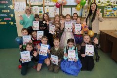 Zdjęcie grupowe Uczniów klasy 2e. Na tle karnawałowej dekoracji stoją Dzieci przebrane m.in. za księżniczki, żołnierza i piłkarza.