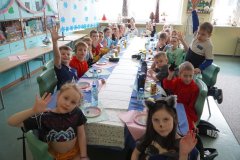 Zdjęcie grupowe Uczniów klasy 1e. Przy stole siedzą Dzieci przebrane m.in. za superbohaterów, koty i księżniczki.