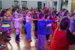 Dzieci z różnych klas podczas zabaw tanecznych na sali gimnastycznej.