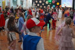 Dzieci z różnych klas podczas zabaw tanecznych na sali gimnastycznej.