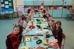 Zdjęcie grupowe Uczniów klasy 3c. Przy stole siedzą Dzieci przebrane m.in. za biedronkę, agentów specjalnych i sportowców.