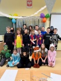  Zdjęcie grupowe Uczniów klasy 3f. Na tle karnawałowej dekoracji stoją Dzieci przebrane m.in. za superbohaterów, postacie z gier, sportowców i zwierzątka.