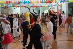 Tańczący uczniowie wśród balonów na sali gimnastycznej.