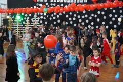 Tańczący uczniowie wśród balonów na sali gimnastycznej.