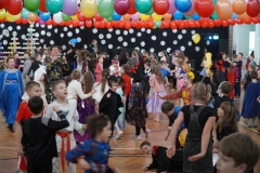 Tańczący uczniowie wśród balonów na sali gimnastycznej.