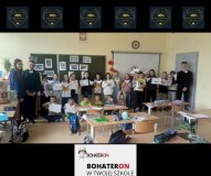 W sali lekcyjnej stoi duża grupa dzieci (uczniowie klasy 3) trzymających             w dłoniach swoje prace: rysunki, karty pracy oraz złożone papierowe gołąbki. Za nimi znajduje się tablica z przypiętymi fotografiami związanymi z Powstaniem Warszawskim. Po obu stronach grupy stoją wolontariusze prowadzący zajęcia.