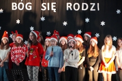 Szkolny chór śpiewa kolędę, w tle napis "Bóg się rodzi".