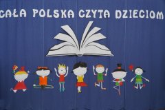 Na niebieskim tle napis Cała Polska Czyta Dzieciom. Po napisem ilustracja otwartej książki i 7 sylwetek dzieci.