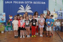 Na tle dekoracji stoi grupa dzieci z nauczycielami/ Laureaci konkursu czytelniczego.
