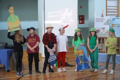 Na tle dekoracji stoi grupa dzieci przebrana za postaci z wiersza ,,Rzepka” i prezentuje fragment przedstawienia.