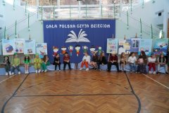 Na tle dekoracji siedzi grupa dzieci przebrana za postaci z wiersza ,,Rzepka” J.Tuwima.