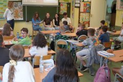 Uczniowie klas starszych na tle wyświetlonej prezentacji czytają uczniom klasy  2d fragmenty literatury dziecięcej.