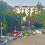 Ujęcie z lotu ptaka na grupę uczniów siedzących i czytających przed budynkiem szkoły.
