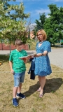 Nauczyciel czyta z uczniem na terenie zielonym przed szkołą