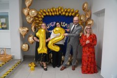 Na tle niebieskiej ścianki ozdobionej  złotymi balonami w kształcie gwiazdek, serc i kół stoją: Dyrektor Szkoły, Wicedyrektorzy oraz Przewodniczący Rady Rodziców. Trzymają w dłoniach duże złote balony z cyframi 1 i 2, tworzącymi numer projektu naszej Szkoły w tegorocznej edycji Budżetu Obywatelskiego.