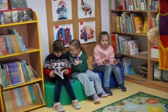 Dzieci przeglądające książki w kąciku czytelniczym.