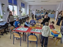 wnętrze biblioteki, przy stolikach dzieci i rodzice bawią się puzzlami i ozobotami, klockami LEGO.