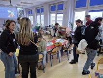 wnętrze biblioteki, bibliotekarze rozmawiają z grupą rodziców, dzieci przy stolikach zajęte są zabawą ozobotami.