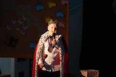 Chłopiec w stroju króla stoi na scenie i mówi do mikrofonu.