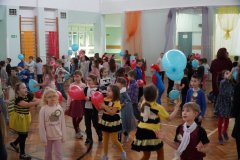 Dzieci w kolorowych strojach bawią się balonami.