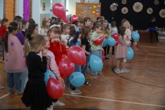 Dzieci w kolorowych strojach bawią się balonami.