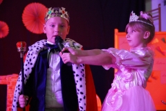 Uczeń w stroju króla i trzymająca mu mikrofon dziewczynka w stroju księżniczki