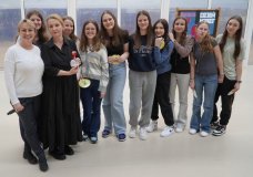Nauczycielki i uczennice pozują do wspólnego zdjęcia podczas obchodów Dnia Kobiet w SP 22 Płock. Jedna z kobiet trzyma pamiątkową statuetkę, a dziewczęta uśmiechają się, trzymając symboliczne medale. W tle widoczna jest dekoracyjna tablica z napisem "Dzień Kobiet".