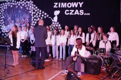 Grupa ludzi śpiewająca przed sceną, z entuzjazmem wyrażająca radość i wspólnotę.