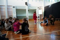 Uczennice z klasy trzeciej demonstrują na manekinie, jak należy udzielić pierwszej pomocy. Prowadząca udziela dodatkowego instruktażu słownego.