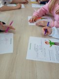 blat stołu, na którym widać formularze krzyżówki i dłonie dzieci z pisakami, uczniowie rozwiązują zadanie