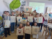 zdjęcie grupowe - klasa 3f z wychowawcą oraz z prowadzącą warsztaty pozuje do wspólnego zdjęcia, w rękach prezentują pokolorowane torby bawełniane, w tle baner z napisem „Bądźmy eko z biblioteką”