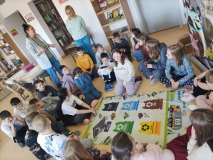 Grupa dzieci siedzi wokół planszy i gra w ekosegregację.