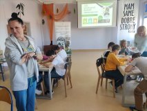 Grupa dzieci przy stołach maluje bawełniane torby.